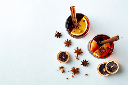 Two glasses of warm mulled wine or cider with orange slices, cinnamon sticks, and star anise scattered around.の写真素材