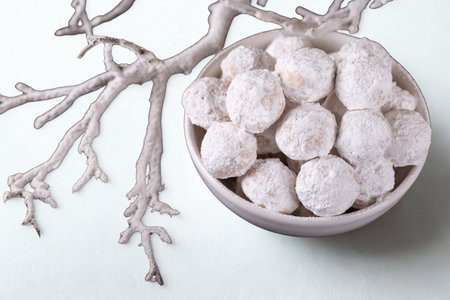 A close-up shot of a decorative bowl filled with white, frosted ornaments, accompanied by a silver, frosted branch.の写真素材