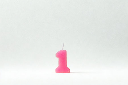 A bright pink candle shaped like the number one stands alone against a clean white backdrop, ready for a celebration.の写真素材