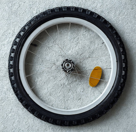 A detailed view of a bicycle wheel, showcasing its tire, spokes, hub, and a bright orange reflective spoke cover.の写真素材