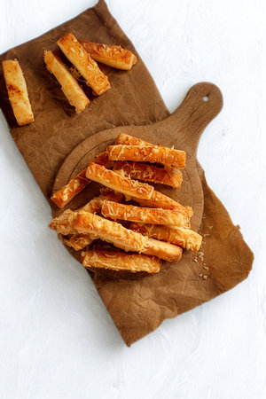 Golden brown, oven-baked cheese sticks are piled high on a small round cutting board, with a few more scattered on a larger board.の写真素材