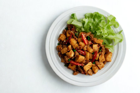 A close-up overhead shot of a flavorful stir-fry dish served with a side of crisp lettuce on a white plate.の写真素材