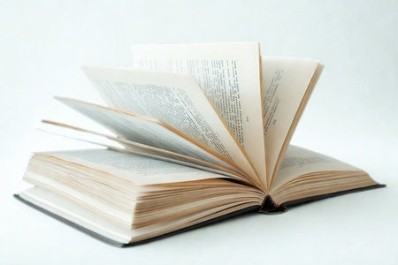 An open book with aged pages, some pages are caught in motion, suggesting a breeze or turning.の写真素材