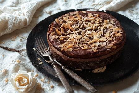 A close-up overhead view of a rich chocolate cake on a dark plate, garnished with a generous topping of crumble and nuts.の写真素材