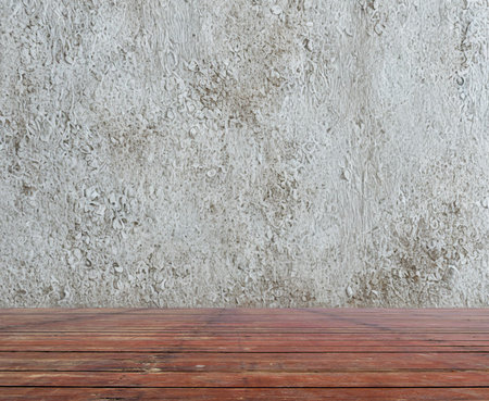 A close-up view of a dark wooden plank surface in the foreground with a textured gray wall behind it.の写真素材