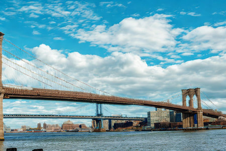 A majestic view of the Brooklyn Bridge with its stone towers and steel cables stretching across the water.の写真素材