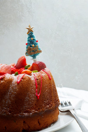 A delicious bundt cake topped with fresh strawberries and a festive miniature Christmas tree, ready for a holiday celebration.の写真素材