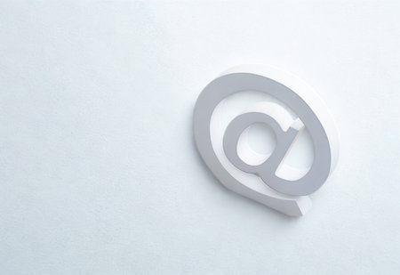 A single, light gray at symbol is prominently displayed against a stark white, minimalist background with subtle shadow.の写真素材