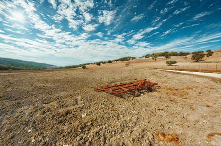 A vast, dry, and rocky terrain stretches towards rolling hills under a vibrant blue sky filled with dynamic, white clouds.の写真素材