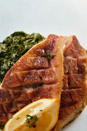 A close-up of a perfectly grilled fish fillet served with a side of vibrant creamed spinach and a fresh lemon wedge.の写真素材