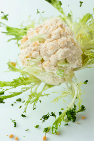 A close-up shot of a whole vegetable with vibrant green leaves and scattered herbs on a light blue background.の写真素材