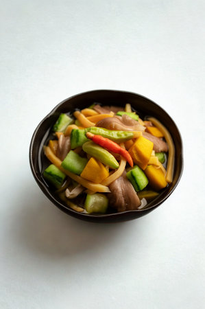 A close-up overhead view of a dark bowl filled with a vibrant mix of sautéed bell peppers, onions, and other vegetables.の写真素材