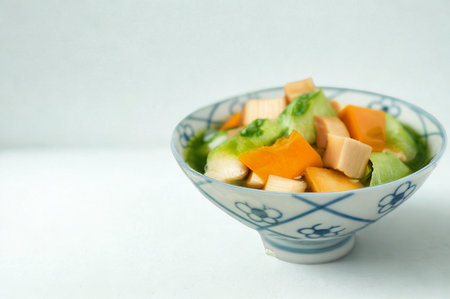 A vibrant mix of chopped fruits served in a patterned ceramic bowl against a clean white background.の写真素材
