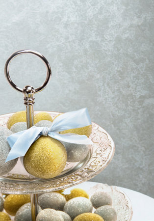 A close-up of a tiered dessert stand holding small, round pastries decorated with a ribbon against a textured gray background.の写真素材