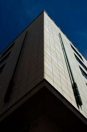 Low angle view of a modern office building against a blue sky.