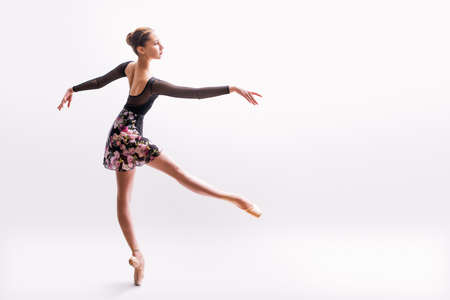 Ballerina in a light dress is dancing on a colored background with backlightの写真素材