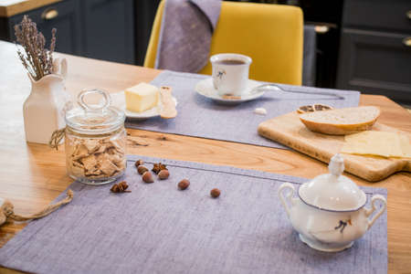 on a linen towel on a wooden table, a simple breakfast of two mugs of coffee, and slices of bread and cheeseの写真素材