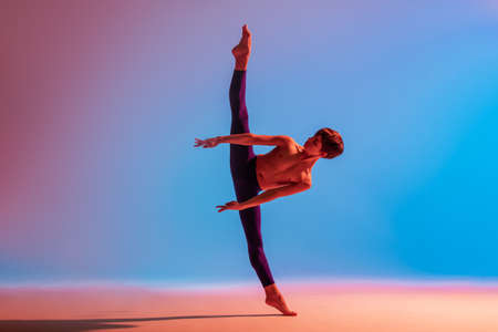 teenage ballet dancer dances barefoot under a colored light.の写真素材