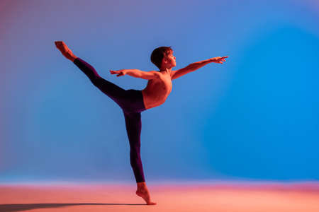 teenage ballet dancer dances barefoot under a colored light.の写真素材