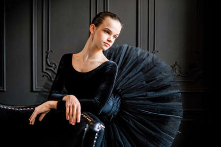 Portrait of a young ballerina girl in a black tutu on a dark backgroundの写真素材
