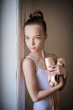 young slender ballerina in a white tutu dances on pointe shoes in a spacious, bright room with large windows.の写真素材