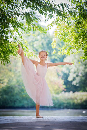 Cute little ballerina in a pink dress in summer outdoorsの写真素材