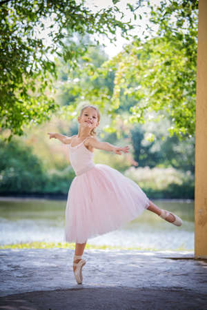 Cute little ballerina in a pink dress in summer outdoorsの写真素材