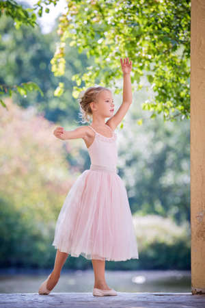 Cute little ballerina in a pink dress in summer outdoorsの写真素材