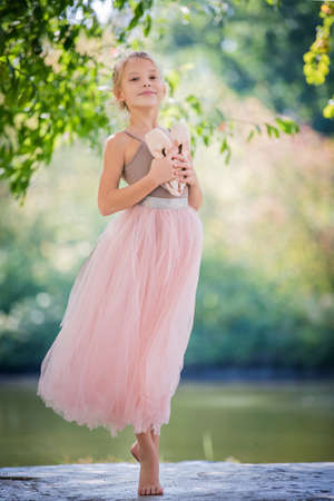 Cute little ballerina in a pink dress in summer outdoorsの写真素材