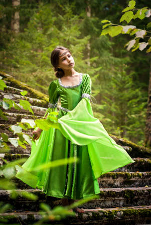 girl in a fairytale elf dress walks barefoot through the forest going down the runes of an ancient staircaseの写真素材
