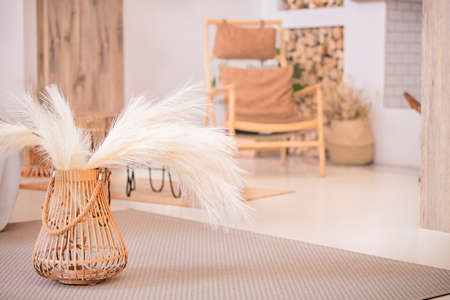 part of brightly lit modern living room with wicker basket with dry bouquetの写真素材