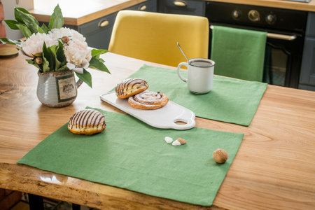 on a green linen towel on a wooden table there is a bouquet of delicate pink peonies and sweet buns lieの写真素材