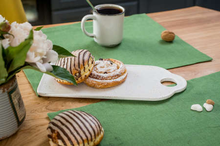 on a green linen towel on a wooden table there is a bouquet of delicate pink peonies and sweet buns lieの写真素材