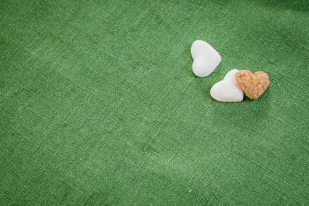 hearts made of refined white sugar and brown sugar lie on the green linen clothの写真素材