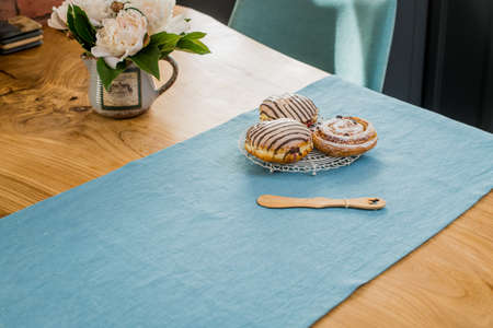 on a blue linen napkin on a wooden table there is a bouquet of delicate pink peonies and sweet buns lieの写真素材