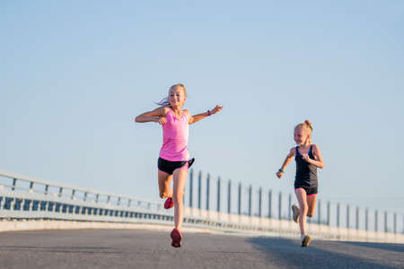 Girls compete on the asphalt road against the evening skyの写真素材