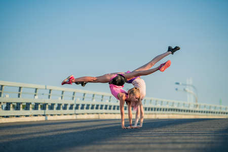Two teenage girls perform an acrobatic element outdoors against a blue skyの写真素材