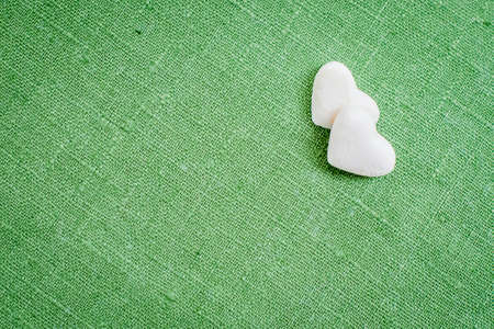 hearts made of refined white sugar lie on the green linen fabricの写真素材