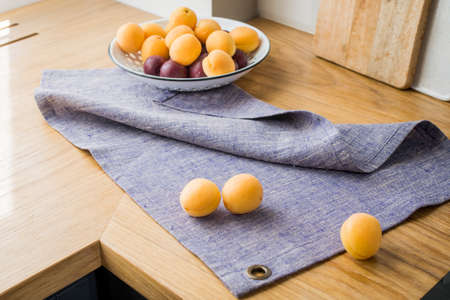 on the table are ripe yellow apricots in a dish and on a lilac linen napkin.の写真素材