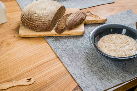 plate of oatmeal and sliced rye bread lie on a wooden tableの写真素材