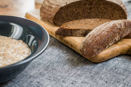 plate of oatmeal and sliced rye bread lie on a wooden tableの写真素材