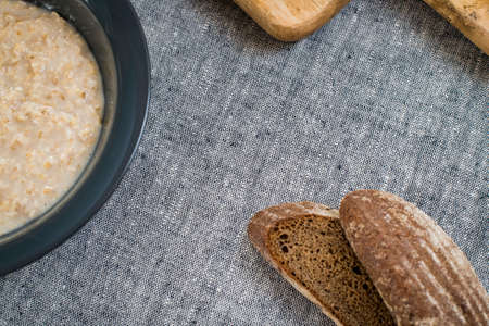 plate of oatmeal and sliced rye bread lie on a wooden tableの写真素材