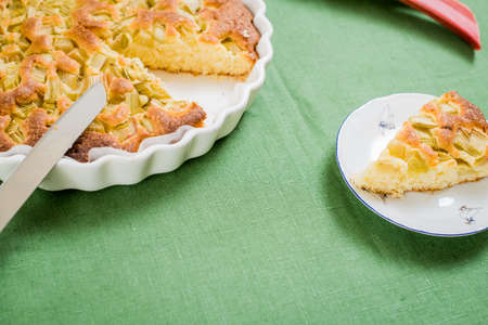 Homemade apple pie Charlotte from rhubarb is in a dish on the kitchen table covered with a green linen tableclothの写真素材
