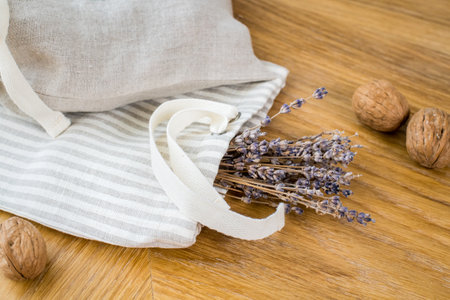 A dried bunch of lavender in a linseed bag lies on a wooden tableの写真素材