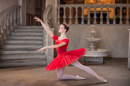 A young ballerina in a red tutu is dancing against the background of the theatrical scenery of the palace.の写真素材