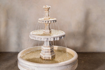 vintage stone multi-tiered fountain with pouring water in the interiorの写真素材