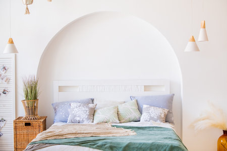 modern bright bedroom interior with bed, pillows and houseplants and decorative basketsの写真素材