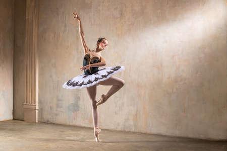 Young ballerina in a white tutu dancing in a spotlight in a vintage sceneの写真素材
