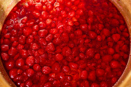 strawberry jam, red berries in syrup close-up in a copper basin