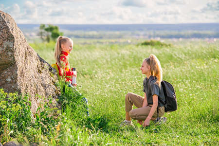 Children with backpacks on a hike on a summer trip to nature. One girl holds a bottle of water in her hands.の写真素材